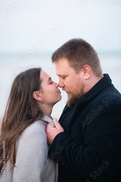 Obraz Romantic moment at beach with caucasian couple embracing in winter clothing