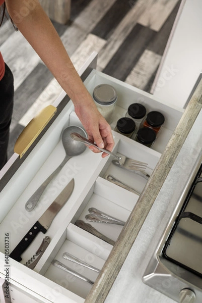 Obraz Open kitchen drawer reveals neatly organized utensils—spoons, ladles, knives, forks and more—within a sleek modern wooden cabinet.

