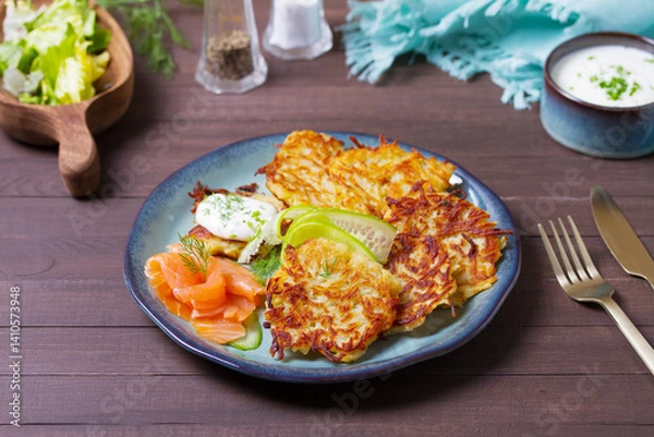 Fototapeta Hash browns with smoked salmon, cucumbers and yogurt. Vegetable fritters, latkes, potato cakes. Vegetable pancakes