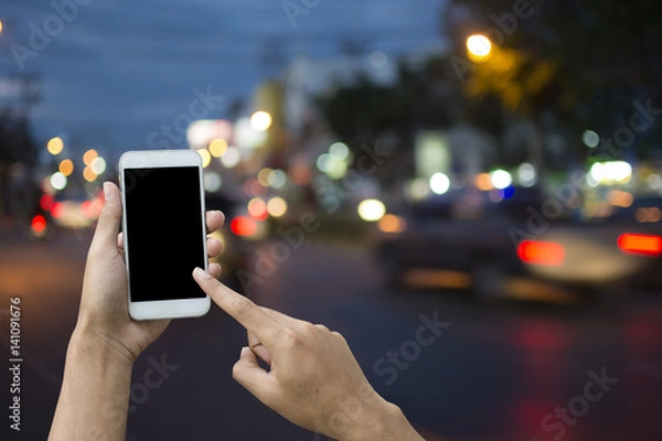 Fototapeta Hand holding smartphone on blur background transport.