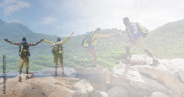 Fototapeta Composite of happy african american couple hiking on rocks, and raising hands looking at the view