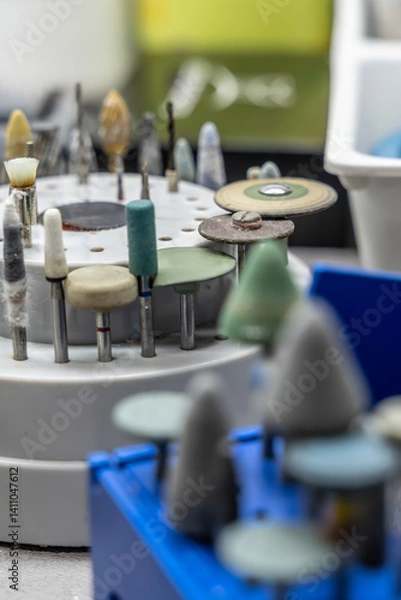 Fototapeta holder featuring an array of dental and rotary tool attachments, including polishing wheels, grinding stones, and brushes. Variety and precision emphasized