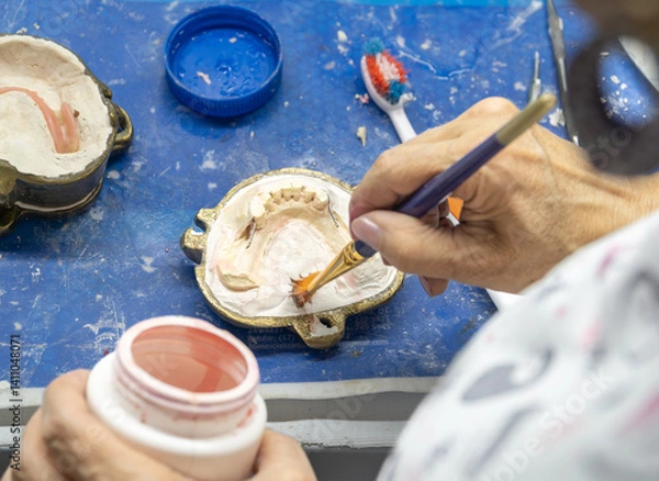 Obraz A skilled dental technician adjusts a dental mold with precision tools in a detailed lab setting, showcasing artistry and craftsmanship
