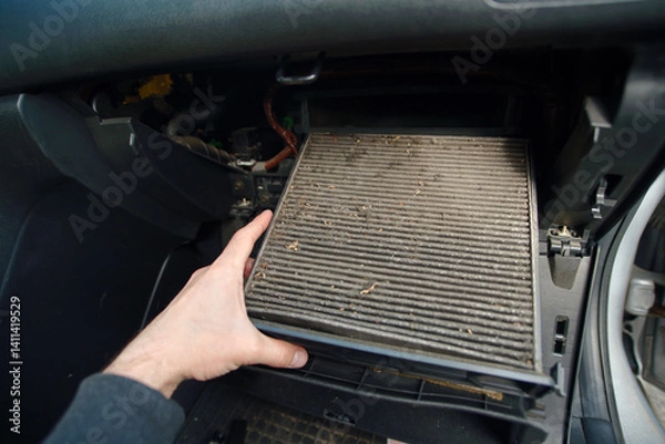 Fototapeta Closeup of person removing dirty cabin air filter from car during regular maintenance showing dust buildup and the importance of clean air in vehicle interiors. Selective focus