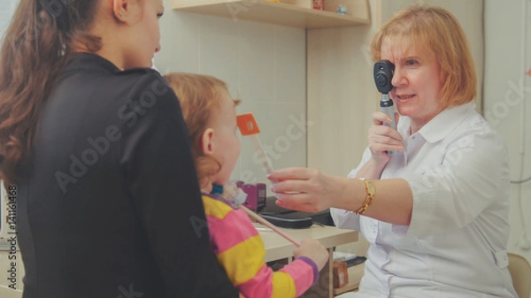 Fototapeta Optometrist checks child's eyesight - mother and child in ophthalmologist room