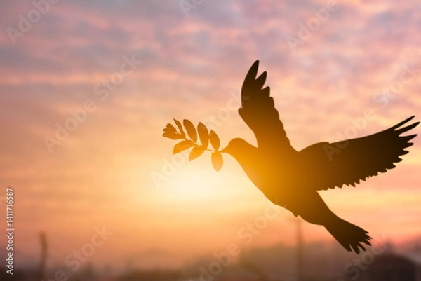 Fototapeta Silhouette shot of a pigeon holding tree leaf flying out over sunset time flare light blurred background, peace and freedom concept, copy space for individual text