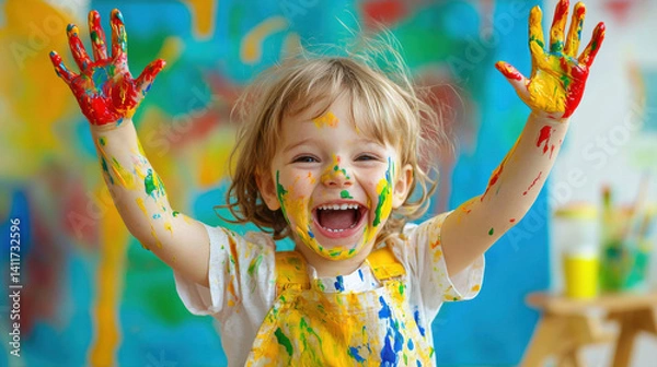 Fototapeta Creative child enjoying painting time, covered in paint, laughing with raised hands