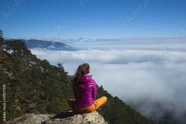 Fototapeta The girl from the cliff faces the clouds