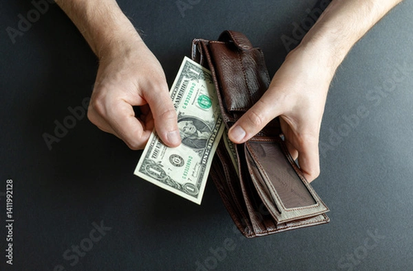 Fototapeta man takes out the last 1 dollar bill from his wallet. abstraction on the topic of high cost of living and bankruptcy