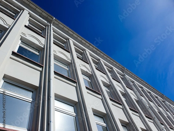 Obraz Concrete plastered building with windows, with afternoon sun. Modern building, urban architectural structure.