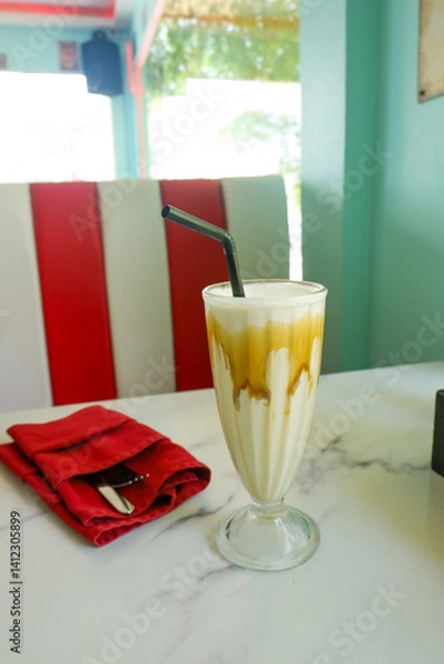 Fototapeta Milkshake with whipped cream with peanuts on the table in the restaurant,Refreshing Caramel Milkshake with Whipped Cream,space for text.