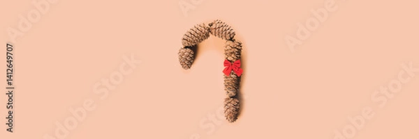 Fototapeta Caramel cane with bow of cedar cones for decoration. Banner.