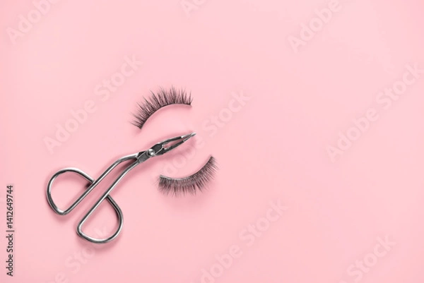 Fototapeta Eyelash curler in the form of scissors and two false eyelashes on pink background.
