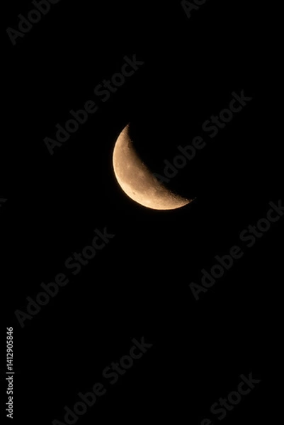 Fototapeta Close-up shot of a waxing crescent moon against a pitch-black night sky. Detailed craters and surface textures are visible in this minimal and captivating lunar image.