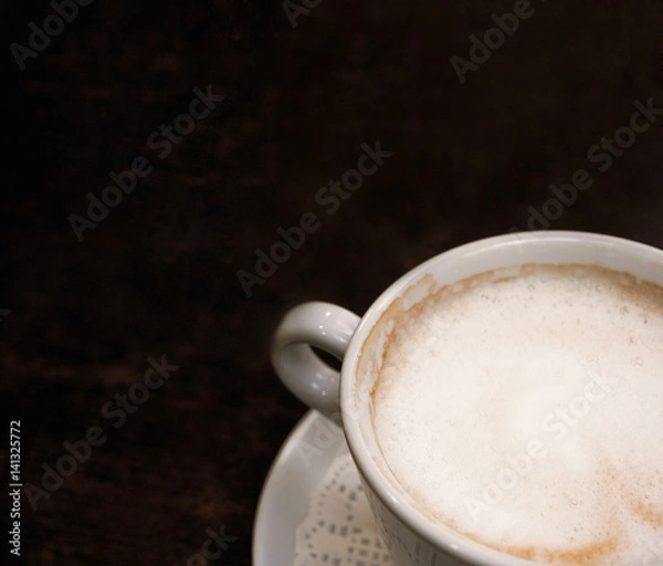 Fototapeta Coffee cup part above view shot with space for text on wooden table.