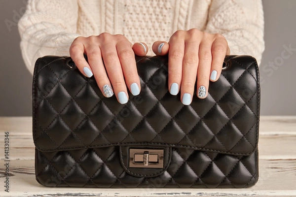 Obraz Klasyczna czarna skórzana torebka i kobiece dłonie z ładnym manicure.