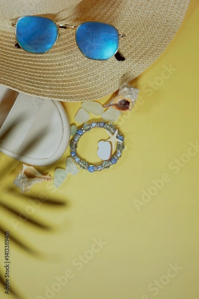 Fototapeta Summer travel vacation mood layout lifestyle spa wellness concept with beach accessories and copy space. Top view flat lay background, including straw hat, sunglasses, sandals, seashells and pebbles