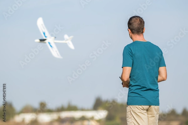 Obraz Man with remote control plane flying in air