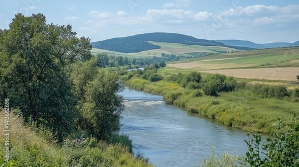 Obraz A beautiful natural landscape with vibrant green trees, a flowing river, and distant hills, leaving an open space for creative designs or text in the center
