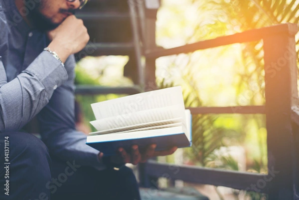 Fototapeta Young handsome beard man reading book. Learning or Education concept.