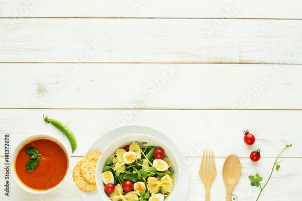 Fototapeta Light summer meal concept. Green salad with pasta, cherry tomato, quail eggs. Cold tomato soup (gazpacho) on a white table. Copy space. 