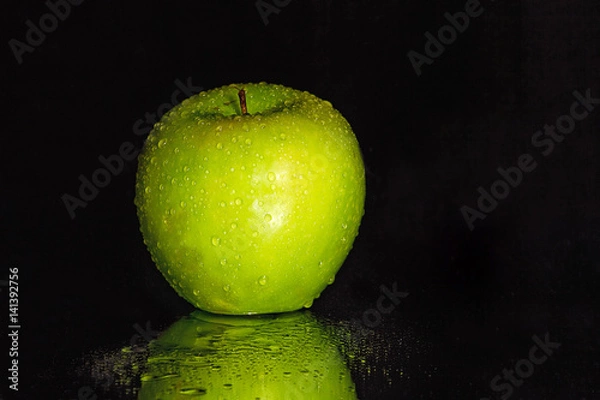 Fototapeta Close-up z zielonym jabłkiem z waterdrops na nim i odbicia poniżej odizolowane na czarno.