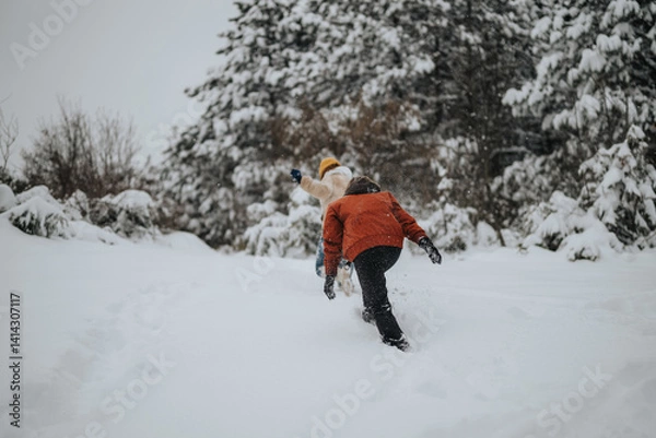 Fototapeta Two people ascending a snow-covered incline in a wintry forest setting, enjoying a seasonal outdoor activity under overcast skies.