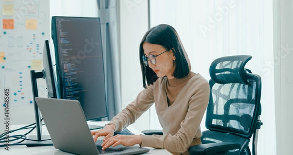 Fototapeta Young adult Asia female freelance eyeglasses typing write prompt AI bot IT app smart program nomad, video game, terminal with coding, user interface, designer, big data center on desktop computer.