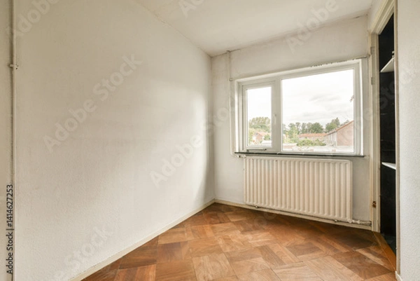 Fototapeta A bright, minimalist room featuring a window and wooden flooring. The walls are painted a soft white, creating a serene atmosphere.