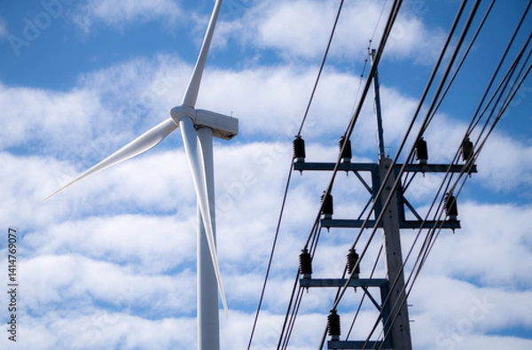 Fototapeta High-voltage electric pylon channels renewable wind energy into grid. Innovation in clean power infrastructure and sustainable environmental transformation. Wind turbines supply green electricity.