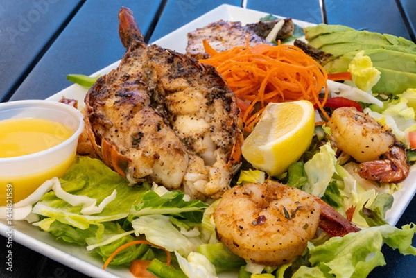 Obraz Seafood Platter with Grilled Lobster, Shrimp an Fish on a Bed of Salad Served with Lemon Dressing and a Wedge of Lemon