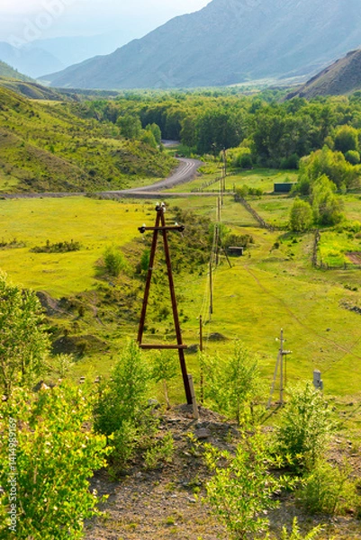 Fototapeta Summer landscape with high-voltage power lines on wooden supports stretching on a Altai mountain valley along Chuysky trakt road, Russia