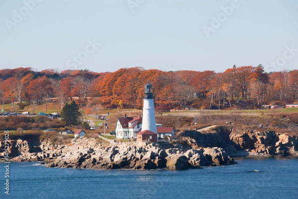Obraz Portland Head Light in Cape Elizabeth, Maine as seen from the Atlantic Ocean on an autumn morning with trees in fall colors. An historic 1791 lighthouse still in operation.