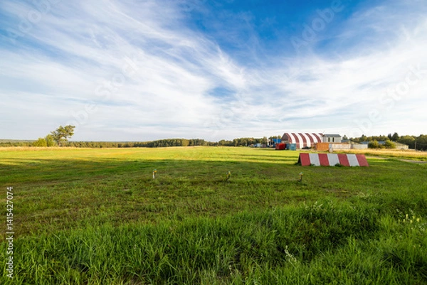Obraz rural airfield with red barn and blue sky