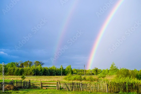 Obraz Double rainbow in the sky over a bright spring field after rain in the countryside