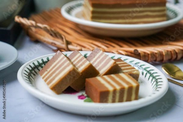 Fototapeta A traditional steamed layer cake with alternating vibrant layers, showcasing a soft, moist texture and rich flavors, perfect for festive occasions.