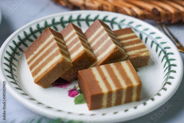 Fototapeta A traditional Indonesian steamed layer cake with alternating vibrant layers, showcasing a soft, moist texture and rich flavors, perfect for festive occasions.