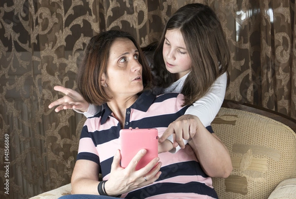 Obraz Mother and daughter in living room arguing and holding tablet