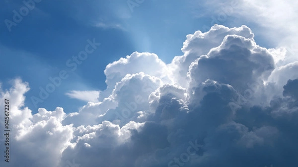 Obraz Fluffy white clouds rise majestically against vibrant blue sky, creating serene and awe inspiring cloudscape. Sunlight peeks through, highlighting cloud edges
