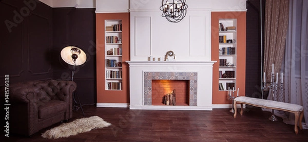 Obraz Luxury interior of home library with brown leather sofa, bookshelves, modern fireplace and art lamp tripod. Sitting room with elegant furniture. Wide angle