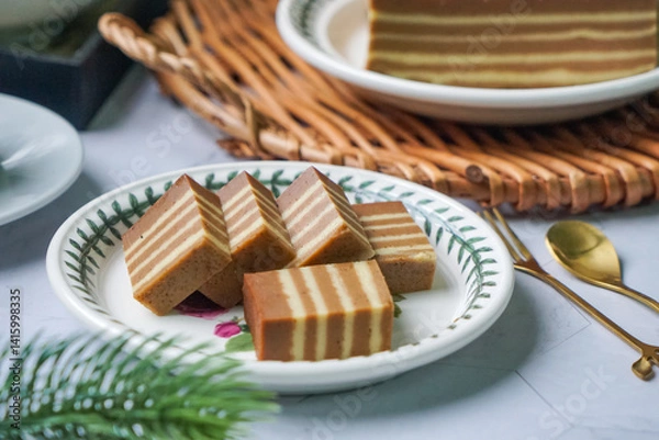 Fototapeta A traditional steamed layer cake with alternating vibrant layers, showcasing a soft, moist texture and rich flavors, perfect for festive occasions.