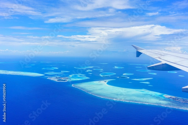 Obraz Scenery from airplane 's window seeing wing of airplane , white clouds , blue sky and Maldives islands