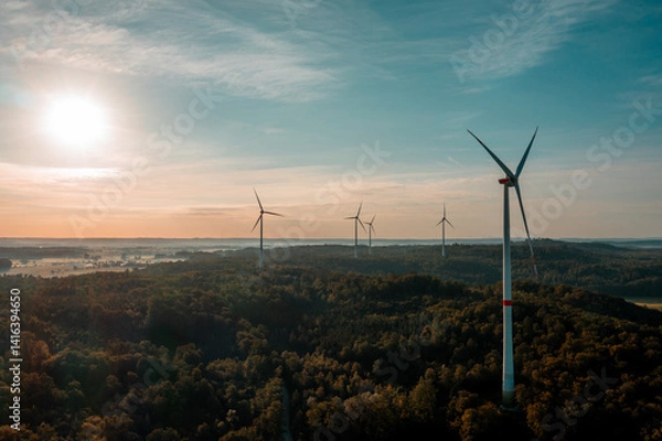 Fototapeta Drone image with wind turbines in the forest at sunrise in Germany