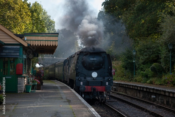 Obraz a battle of Britain class pacific locomotive traveling through a southern station in the uk
