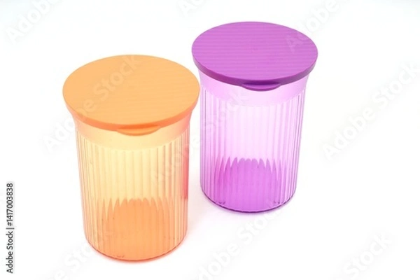 Fototapeta Two brightly colored plastic food storage containers with lids, against a clean white background. These containers are perfect for storing food items and keeping them fresh. 