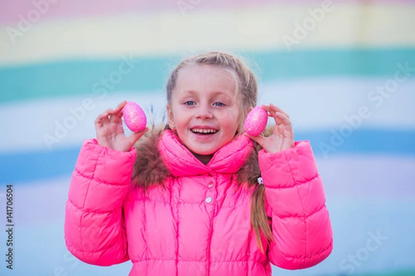Fototapeta Cute pretty girl playing with colored eggs for Easter celebration