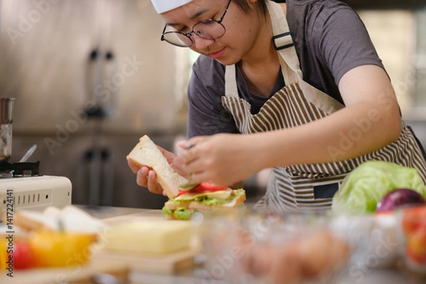 Obraz Focused chef carefully a gourmet sandwich in a professional kitchen with fresh ingredients in view