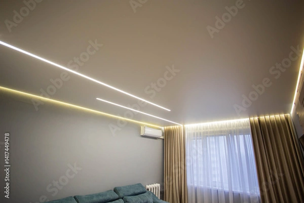 Fototapeta Modern interior of the ceiling with light diode lines against the background of a window with curtains and air conditioning in the hall. Stylish room interior. Copy space for text