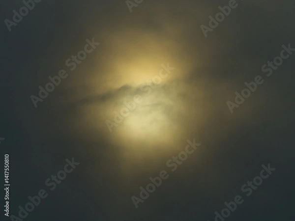 Fototapeta Blurred sun disk behind dark clouds