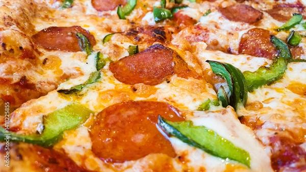 Obraz Pizza with sausage, peppers and cheese. Freshly cooked pizza on the table in a restaurant.